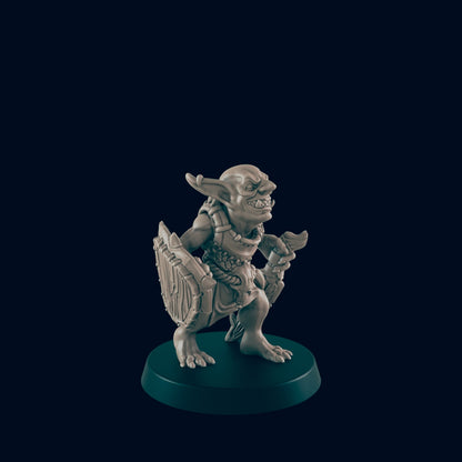 A goblin miniature stands on a base, wielding a shield and dagger. The goblin looks menacing and is set against a dark background.