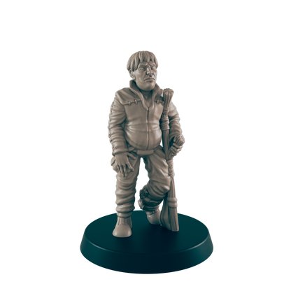 A miniature figurine of a stout boy stands, holding a staff;  it is displayed on a dark circular base.