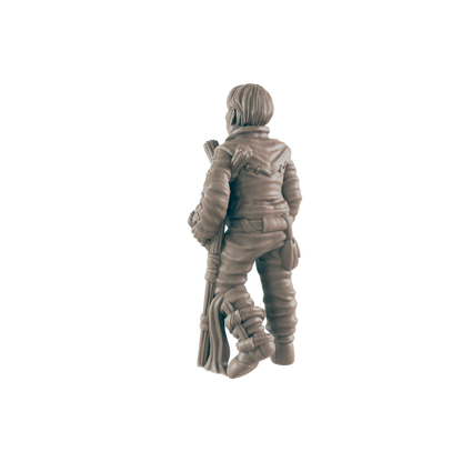 A miniature figurine of a person stands, holding a staff, against a dark background.
