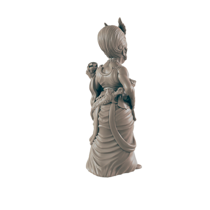 A sculpted female figurine, standing with a back-facing pose against a dark background, wears an elaborate gown and carries a dagger.