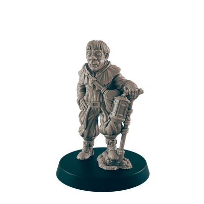 A miniature figurine of a stout, hooded figure stands holding a lantern-topped staff.  The figure is posed on a dark circular base.