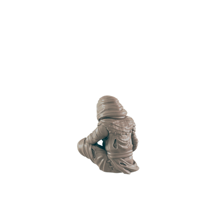 A small, hooded figure sits cross-legged against a black background.  The figure is light beige, appearing to be sculpted.