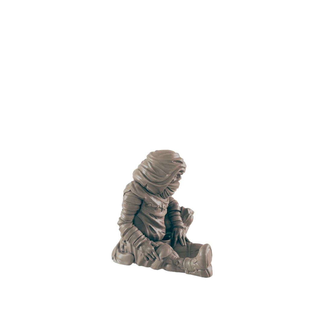 A small, hooded figure sits hunched over, appearing to be examining something in its lap, against a black background.