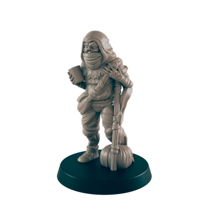 A miniature goblin figure stands on a dark base, holding a cup and a staff with a gourd.  It wears a hooded cloak and tattered clothing.