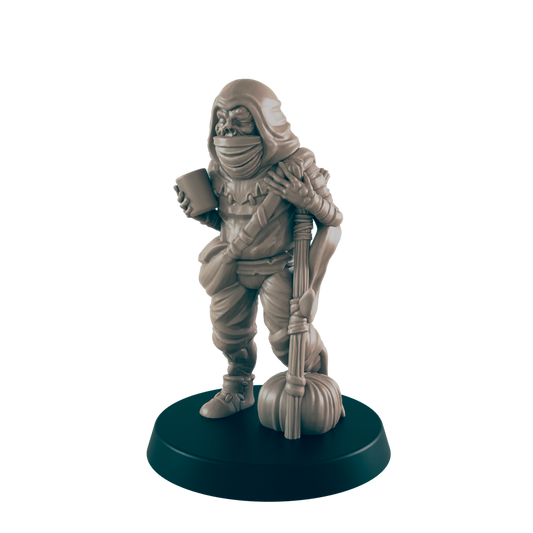 A miniature goblin figure stands on a dark base, holding a cup and a staff with a gourd.  It wears a hooded cloak and tattered clothing.