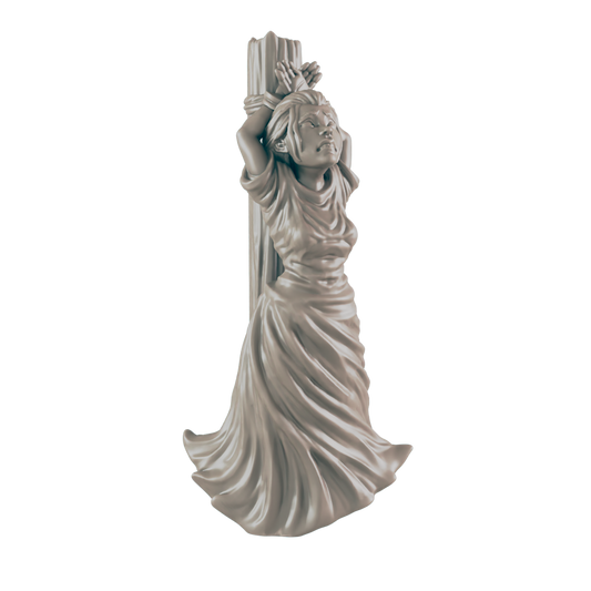 A miniature figurine of a woman, bound to a post, stands against a dark background.