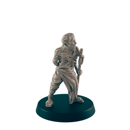 A miniature figurine of a robed humanoid stands holding a staff.  The figure is light beige, positioned on a dark circular base.