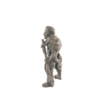 A miniature goblin figurine stands, carrying a staff, against a black background.