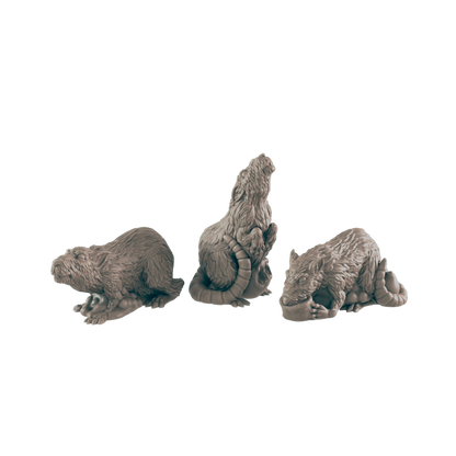 Three rat-like figurines are posed; one is crouched, one sits upright, and one lies down.  They are arranged in a row against a black background.
