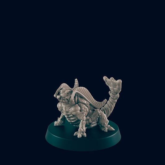 A small, sculpted creature, resembling a grotesque frog-like beast with a segmented tail, sits on a dark circular base against a black background.
