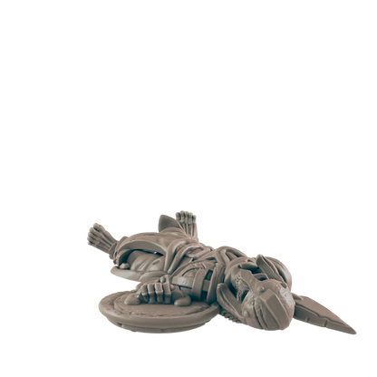 A skeletal warrior miniature lies supine;  it holds a shield, on a dark background.