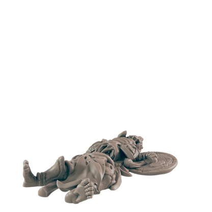 A miniature warrior lies supine; he is fallen, his shield discarded nearby, against a black background.
