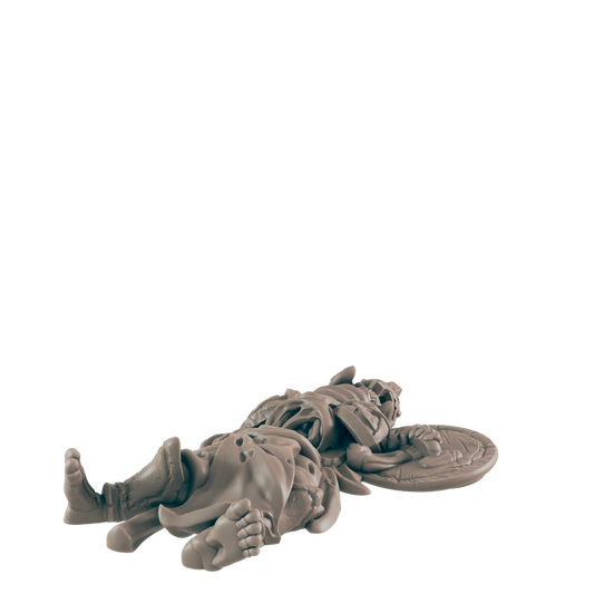 A miniature warrior lies supine; he is fallen, his shield discarded nearby, against a black background.