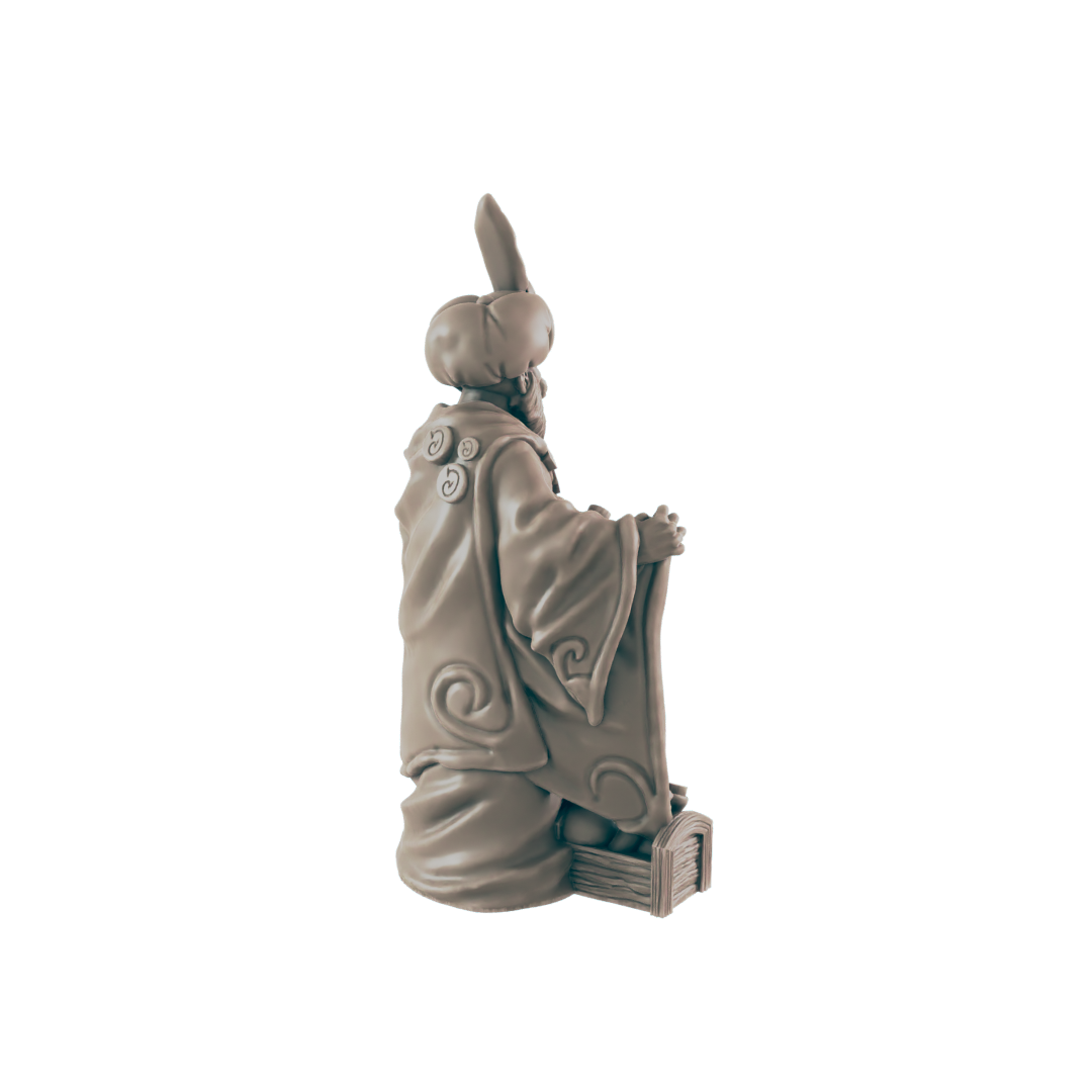 A sculpted figurine of a robed figure sits, appearing to hold a book or scroll, against a black background.