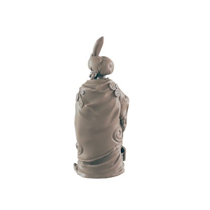 A tan figurine, seemingly a person in a robe and hat, sits against a dark background.