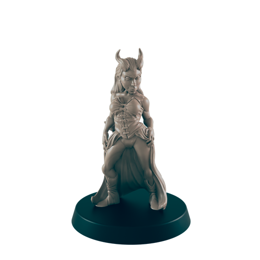 A miniature female figure, horned and cloaked, stands on a round base.  The figurine is sculpted in a pose suggesting confidence or defiance.  The setting is a dark background, highlighting the sculpture.