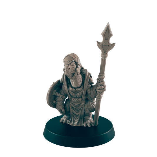A turtle-like miniature figure stands holding a spear; it wears a robe and carries a shield.  The miniature is displayed on a circular base.